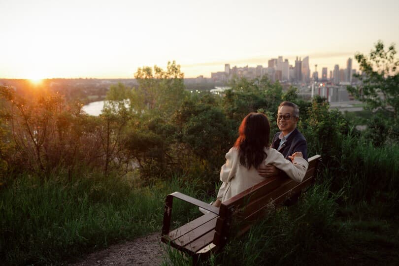 Couple sitting on a bench that overlooks downtown Calgary at sunset