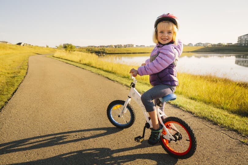 Little girl on her bike on a path at Chinook Gate by Brookfield Residential in Calgary, AB