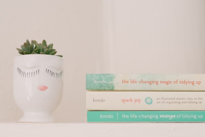 A stack of Marie Kondo books by a succulent
