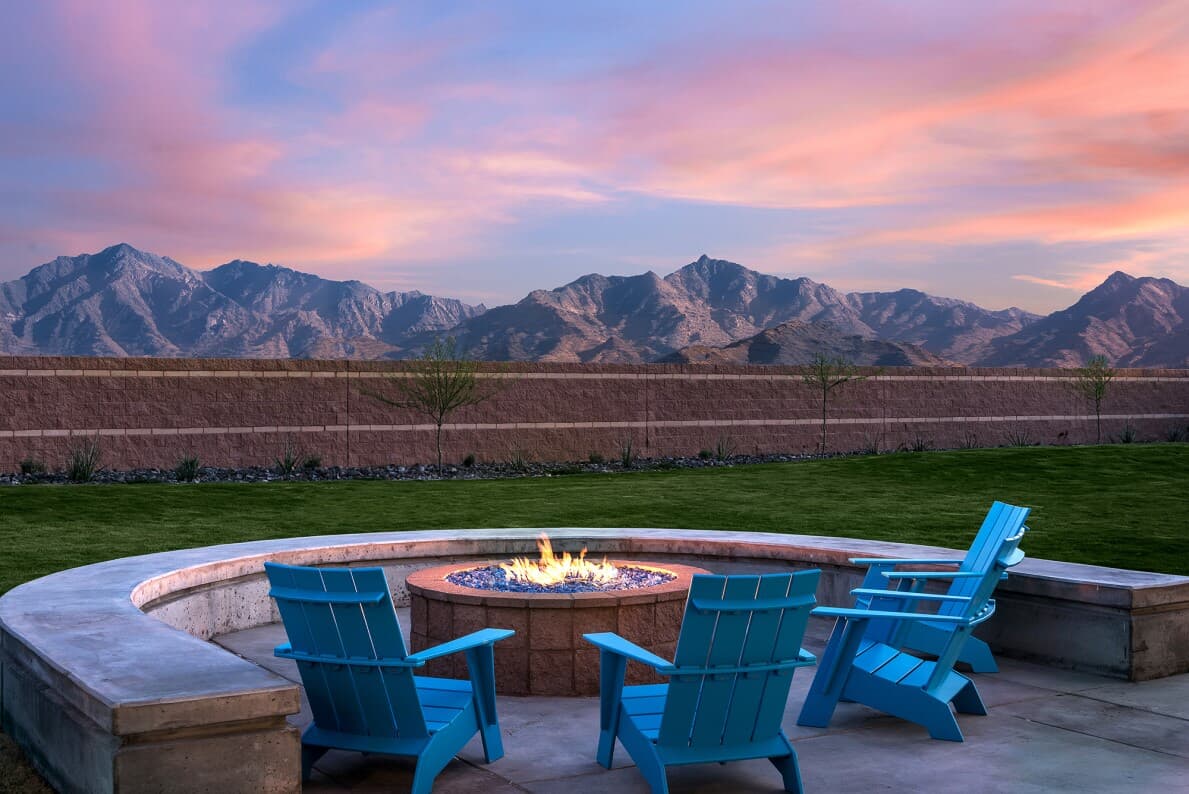 Blue patio chair around a firepit at sunset with Arizona mountains in the back