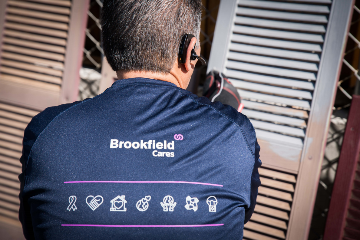 Man repainting shutters and wearing a Brookfield Cares shirt in Denver, CO