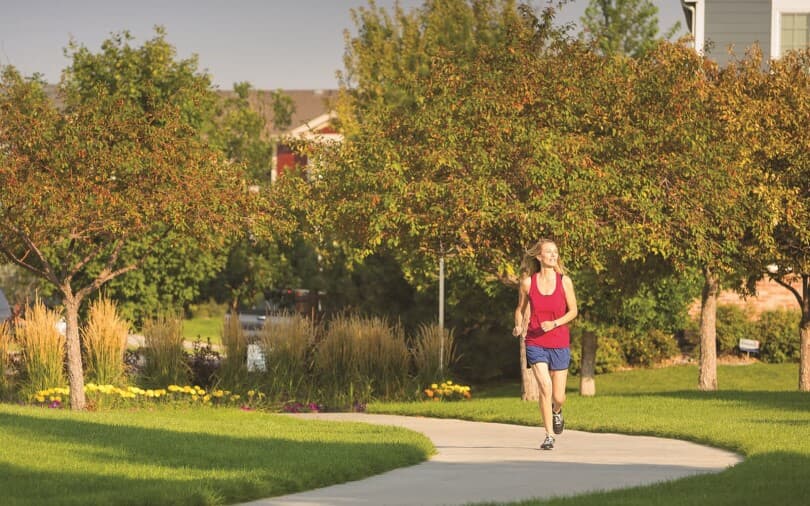 Woman running on a path that goes through Brighton Crossings by Brookfield Residential in Brighton, CO
