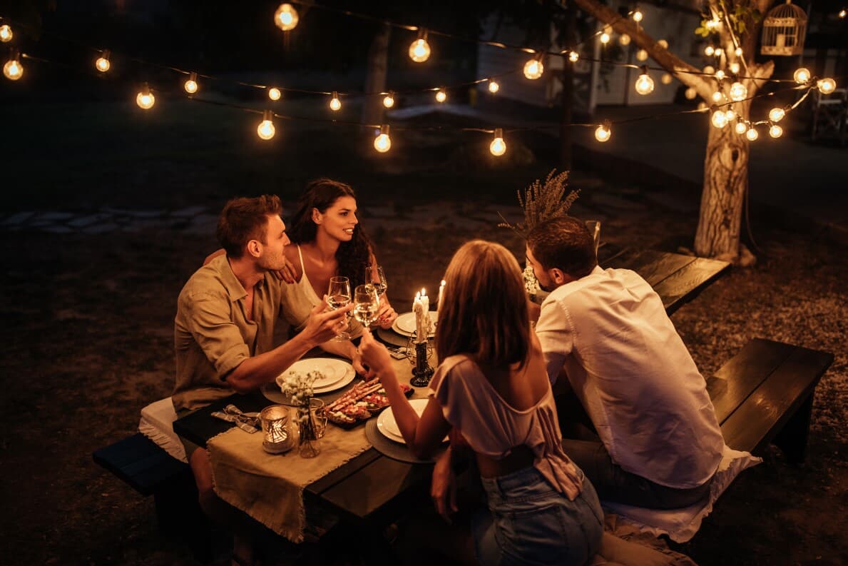 Friends enjoying outdoor dining in a backyard with string lights