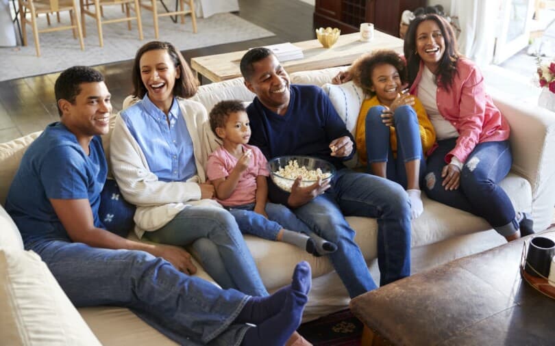 Multigenerational family sitting on a couch smiling and laughing together