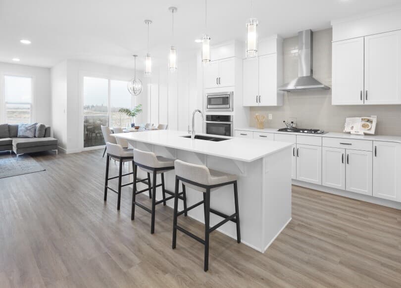 Light and bright white kitchen with wood flooring in Cypress at The Orchards in Edmonton AB