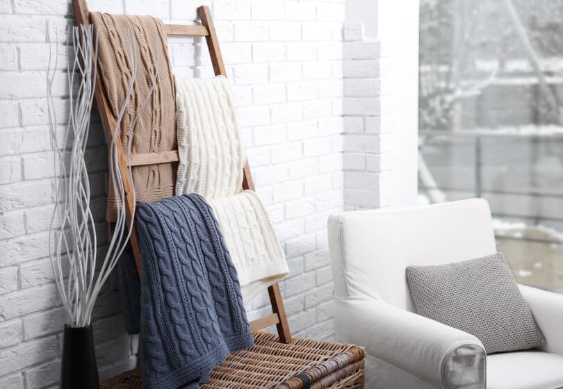 Blankets folded and hung on a wooden ladder