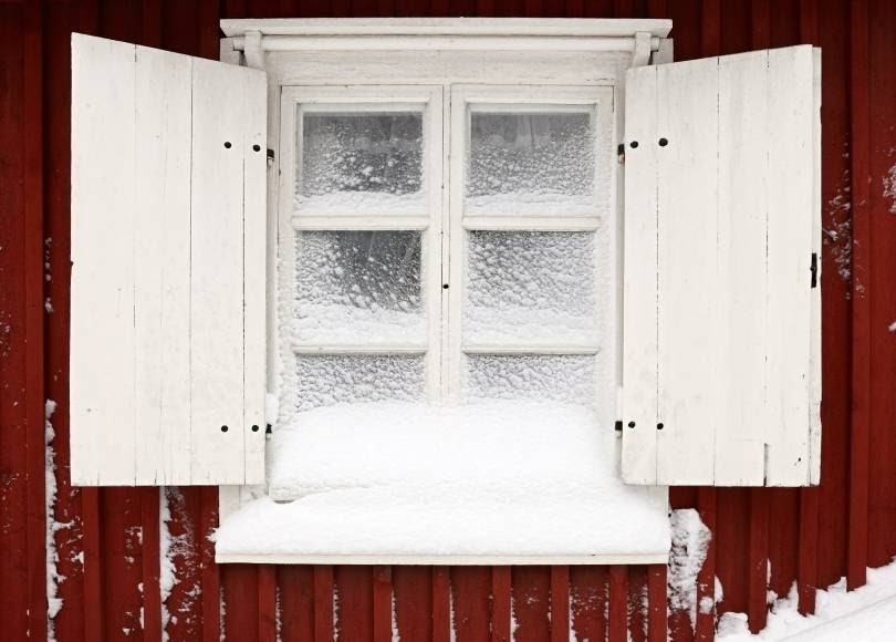 Exterior image of old window and shutters covered in snow concept