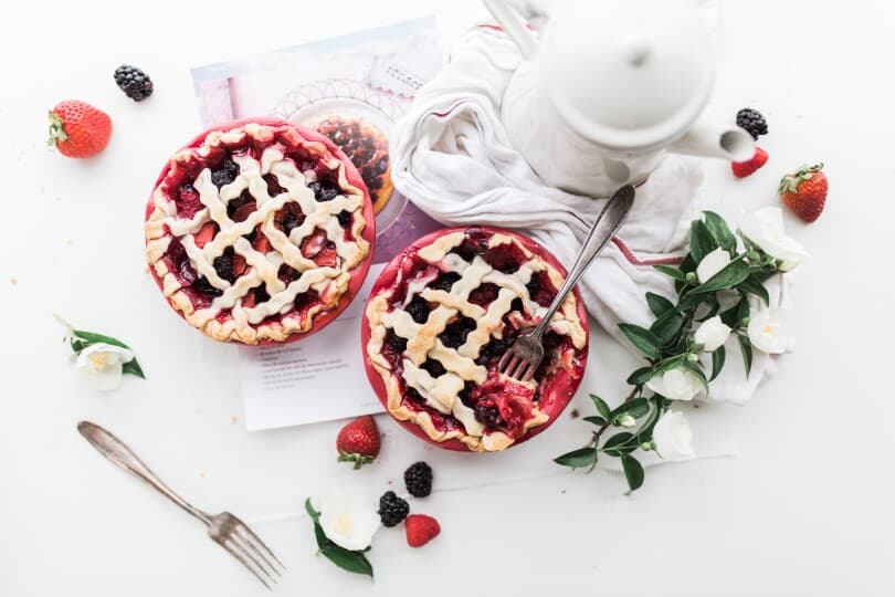 Cherry pies on a table set with fruit and greenery