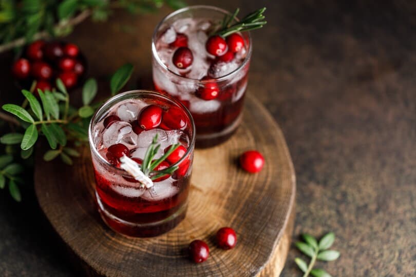 Holiday cranberry cocktail on a wood charger