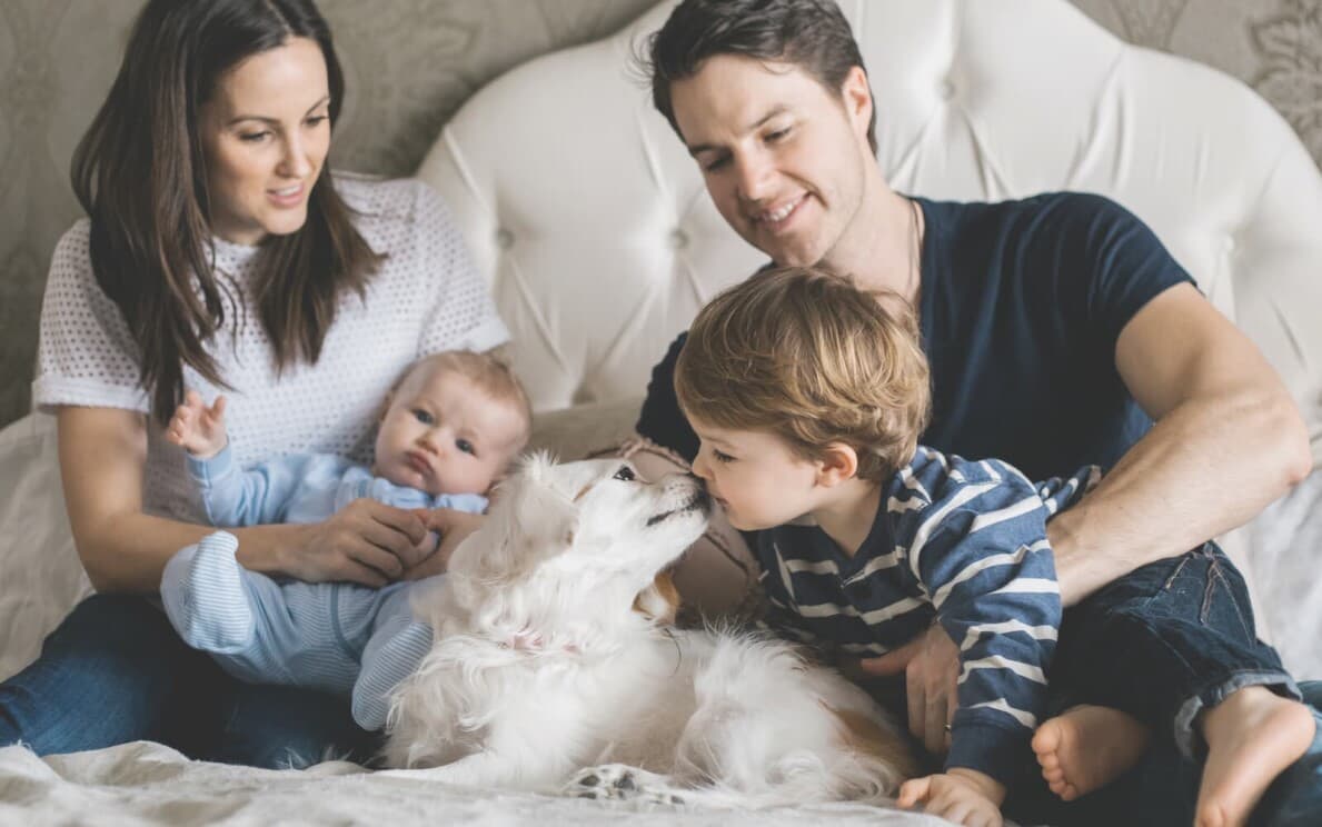 Young family with two kids and a dog on their bed