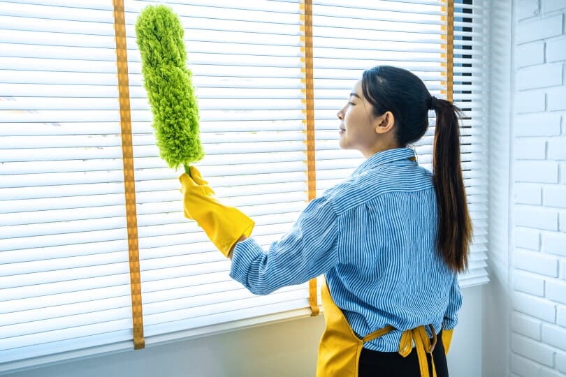 Woman dusting window blinds