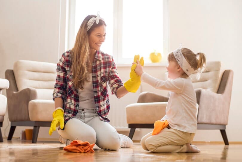 Young mother and daughter cleaning home together and having fun