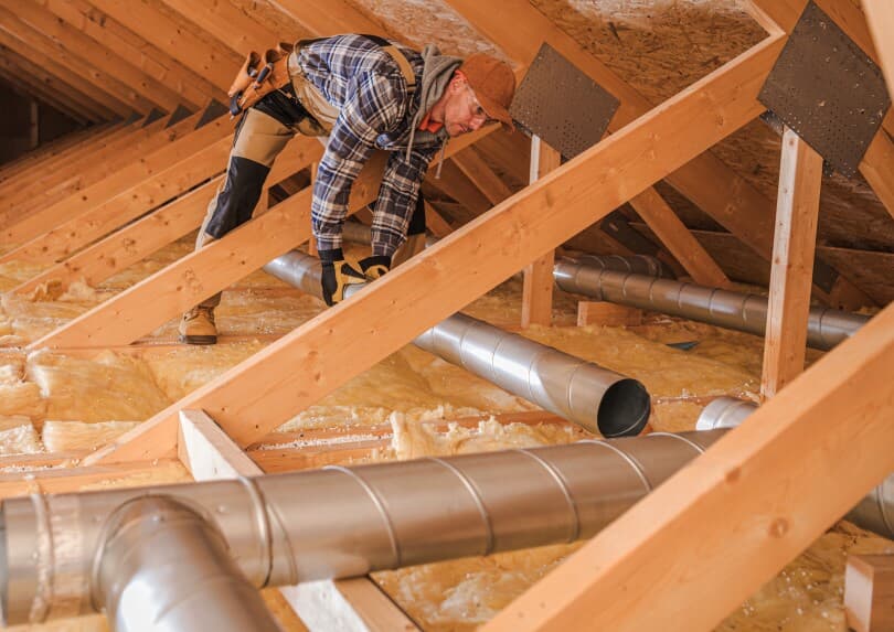Worker installing HVAC ducting in a new construction home