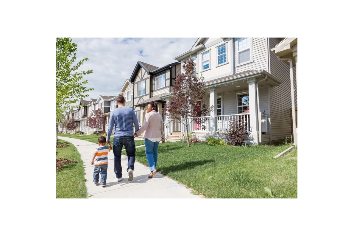 Family holding hands and walking on a sidewalk in their Brookfield Residential community in Edmonton, AB