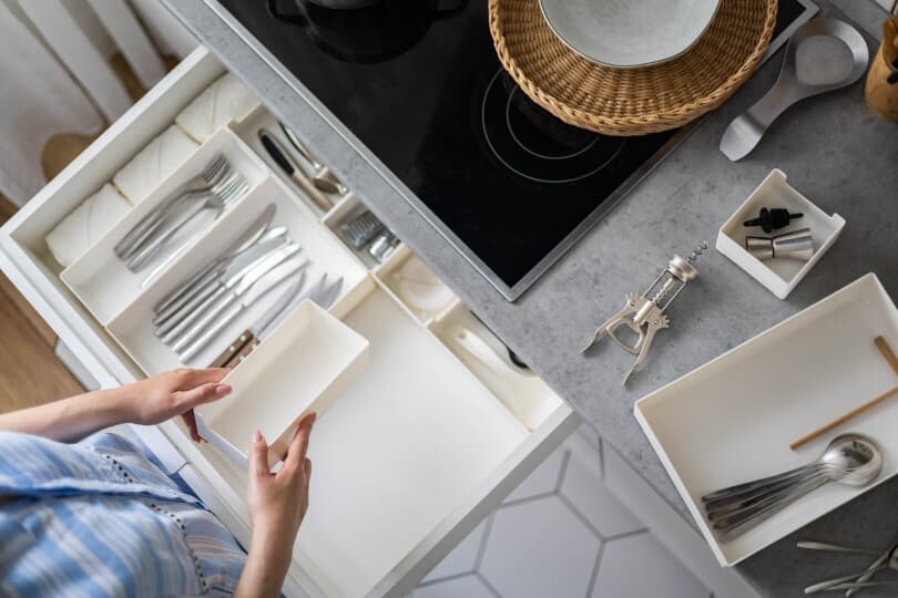 Woman organizing cutlery in a kitchen drawer
