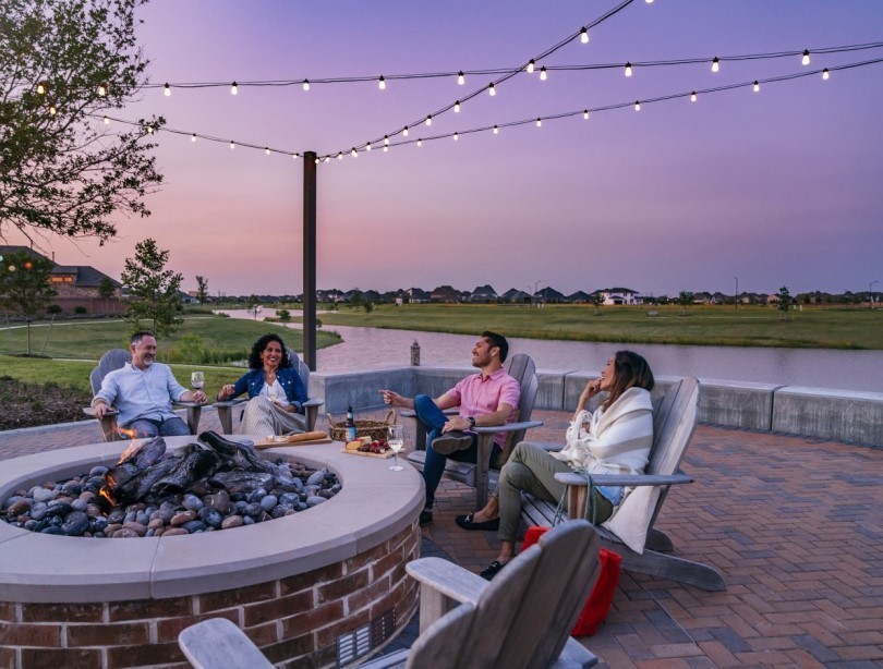 Group of friends around an outdoor fire pit at sunset enjoying wine and beer in Katy TX
