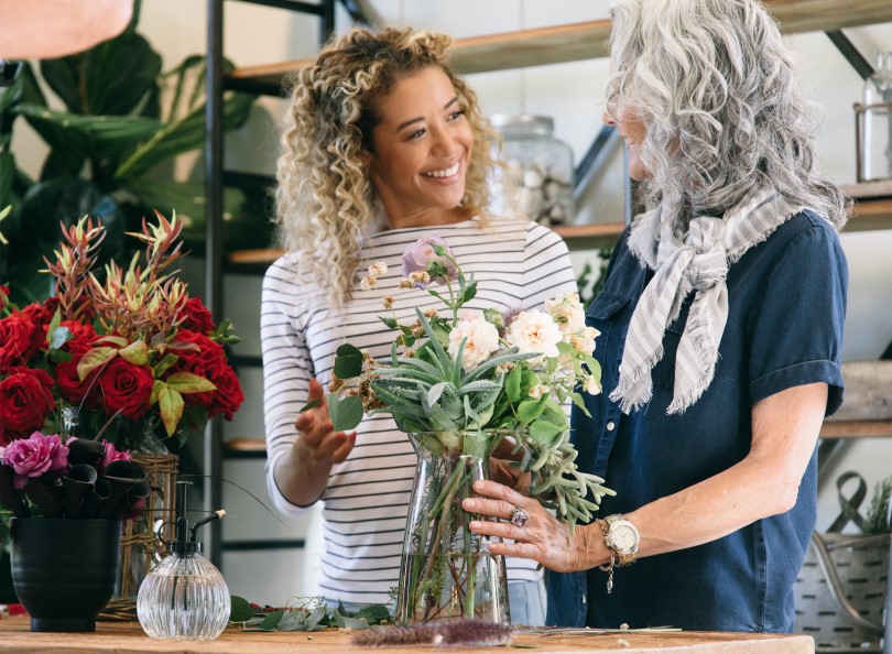 Two women in a flower shop with a bouquet in a vase