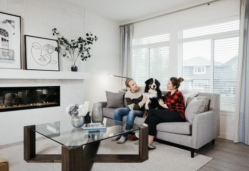 Young couple with their dog on a couch in a Brookfield Residential home at The Orchards in Edmonton