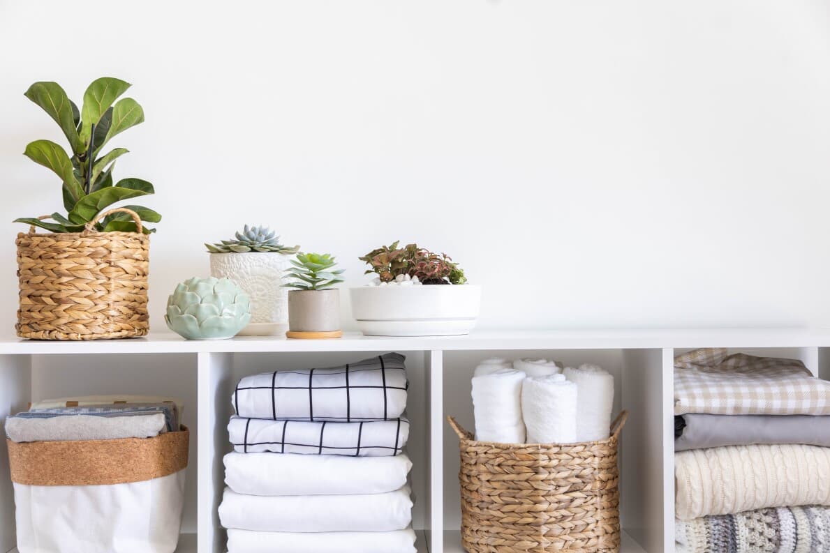 Organized linens in storage with plants on top