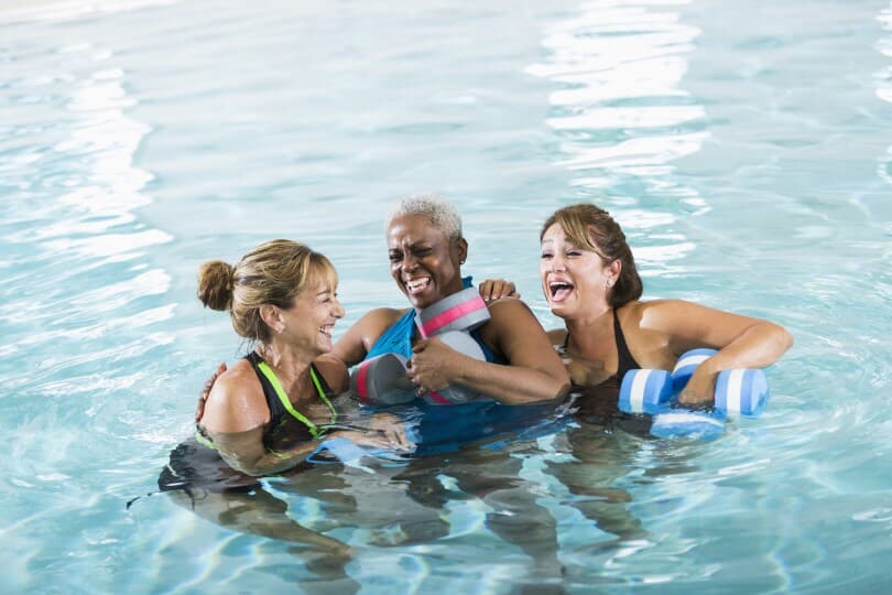 Group of women laughing in a pool with water workout equipment