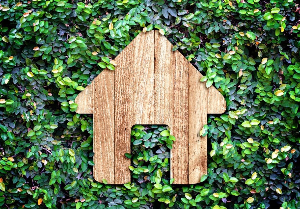 Wooden cutout of a house in front of green shrubbery