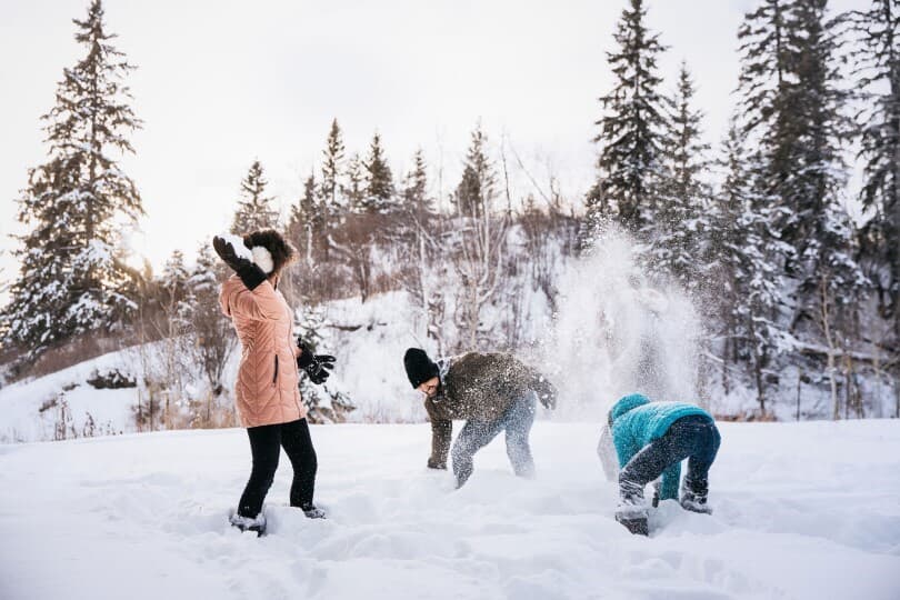 Family having a snow fight in a wooded area