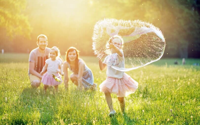 Family blowing bubbles outdoors.