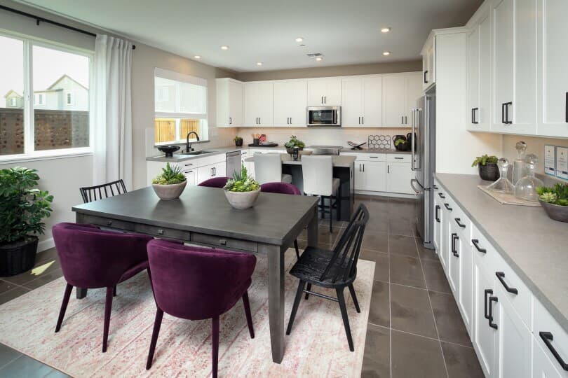 Dining area with purple chairs and white kitchen in Residence 5 at Chandler in Brentwood, CA