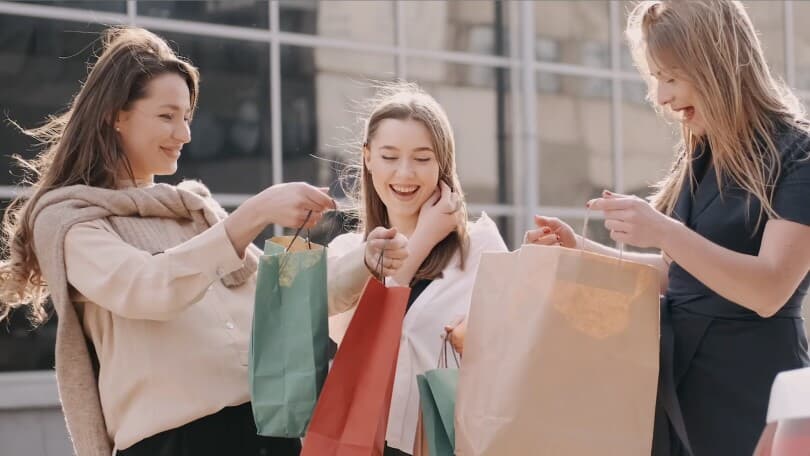Three women laughing and talking holding shopping bags