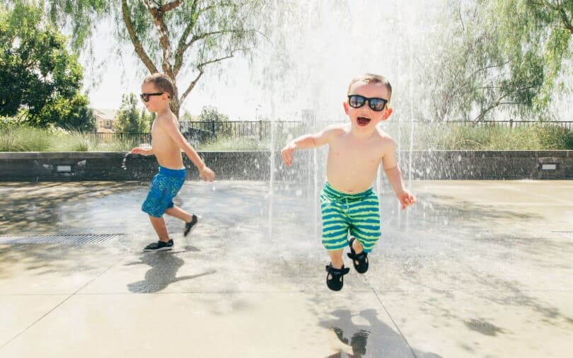 Two little boys playing in the water at a splash pad at New Haven in Ontario Ranch, CA